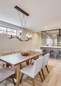 dining room with wooden dining table and grey chairs underneath contemporary chandelier light in Chicago apartment for rent