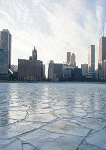 a frozen layer of ice covers Lake Michigan near apartment buildings in downtown Chicago