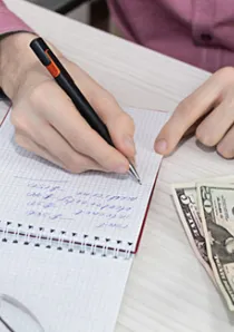 person writing in a steno notebook and calculating security deposit payments for their Chicago apartment