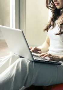 woman in grey tanktop using a silver laptop computer