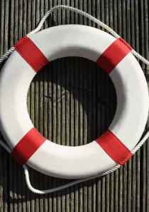 a white and red lifesaver ring hanging on a corrugated metal wall