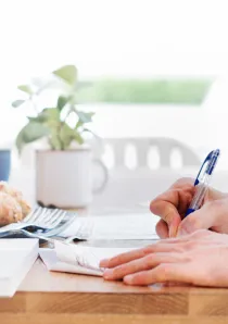 a man signing a document while leaning on a desk