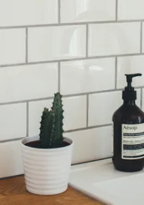 white porcelain tile in kitchen back splash behind chrome faucet and white sink with wood counters