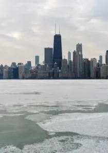 patches of snow and ice float on Lake Michigan with Chicago skyline in background