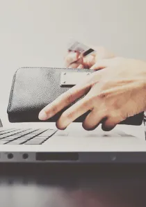 person taking a credit card out of their wallet to pay an apartment utility bill online