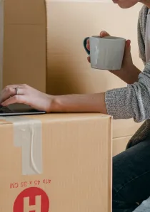 woman using laptop balanced on brown moving boxes