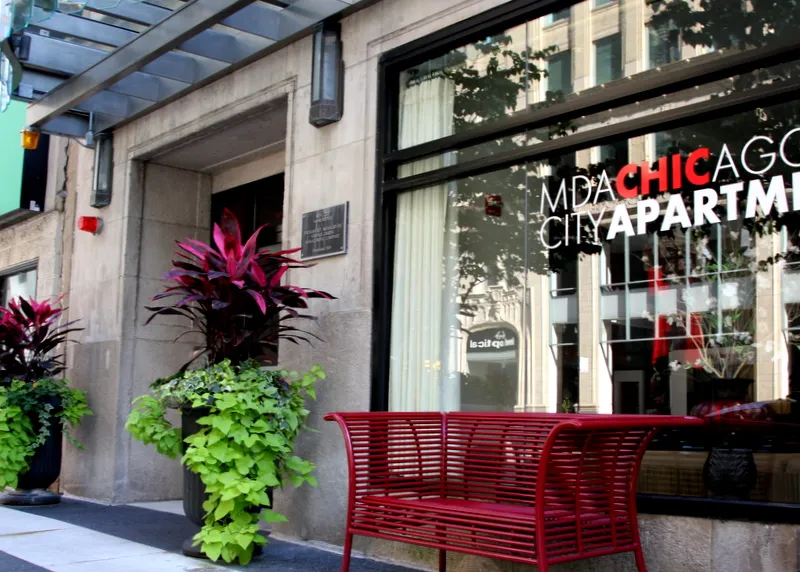 entrance to MDA City Club Apartments with red bench a flowers in pot