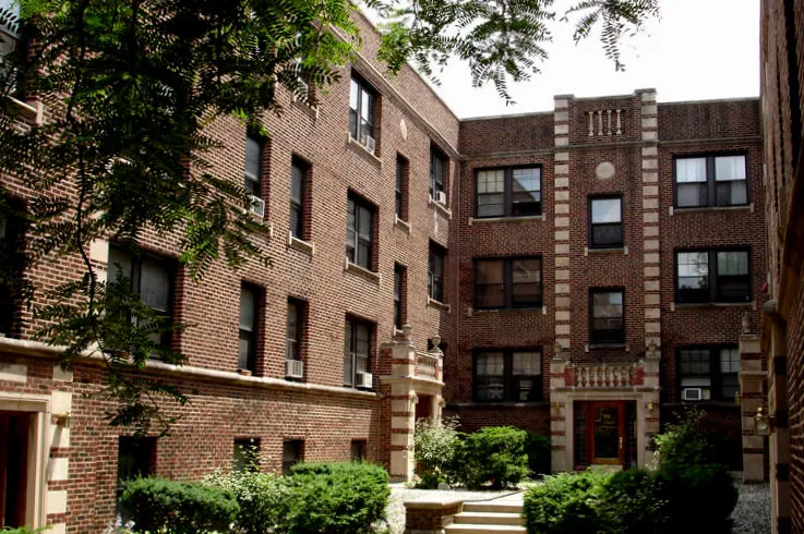 courtyard with trees, bushes and dark brick building at 921-929 W Oakdale