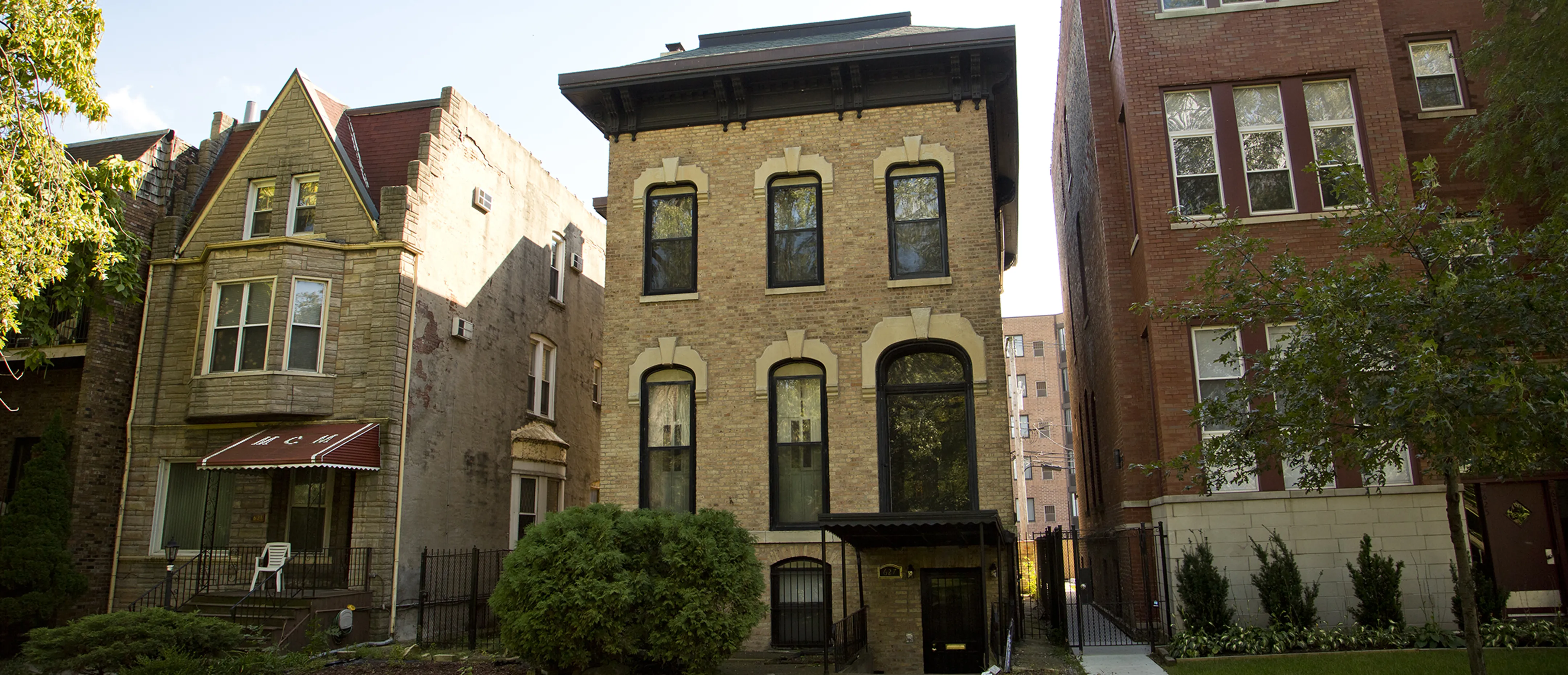 Three brick apartment buildings on a side street with green shrubs in front in the Douglas neighborhood of Chicago.