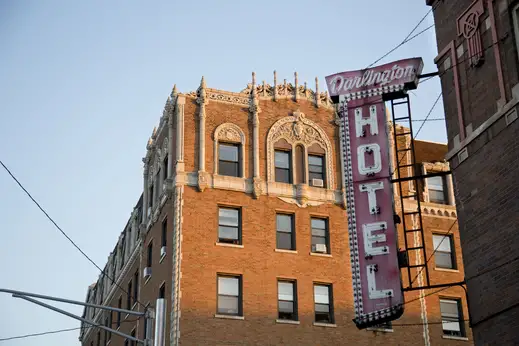 Darlington Hotel with vintage lightbulb sign and apartment buildings in the background in Uptown