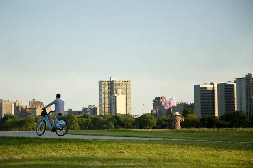 Divvy Bike rider along lakefront bicycle path with cotton candy vendor in Uptown Chicago