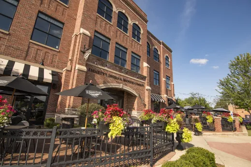 lots of flowers and green bushes in front of outdoor cafe restaurant in front of red brick building in Palatine, Illinois