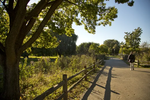 man walking near fence with headphones next to trees in Bowmanville Chicago