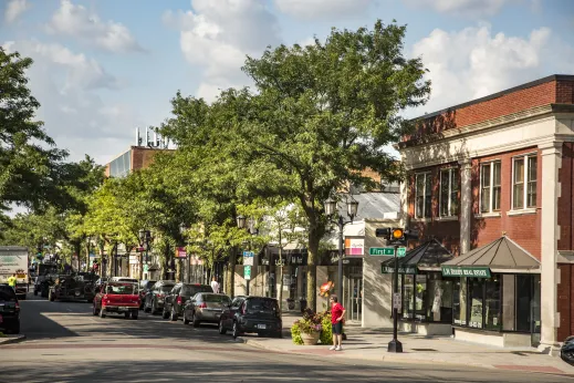 woman crossing street in front of red brick building with storefront in Elmhurst Illinois