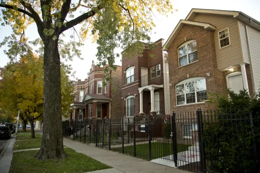 rental homes with black iron fences in front and green grass lawns in Hermosa Chicago