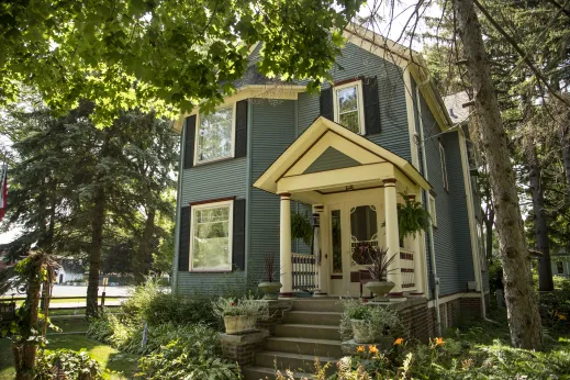 blue frame house with white front door with beautiful front landscaping in Des Plaines, IL