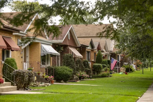 beautiful bright green front lawns of single family homes with awnings over windows and flowers in front in Englewood Chicago