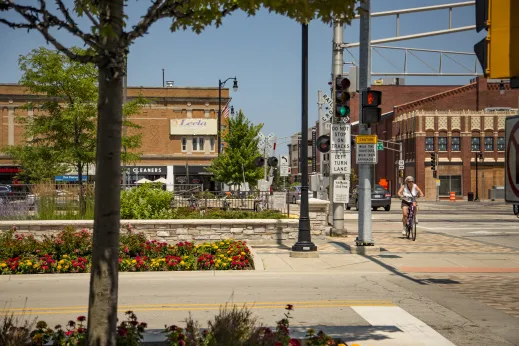 commercial street in downtown Des Plaines, IL with cyclist in street and flowers