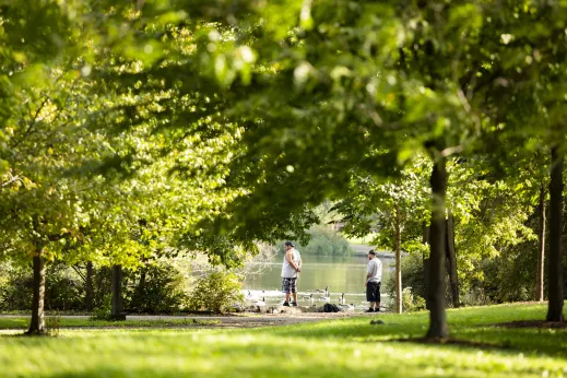 men next to pond with geese and lush with trees and grass in Back of the Yards Chicago