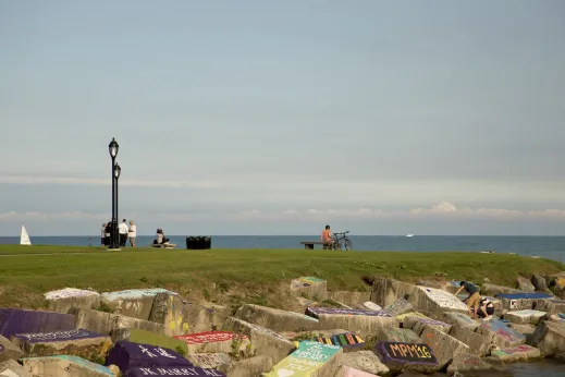 Northwestern University students climbing rocks with graffiti at Lakefill in Evanston