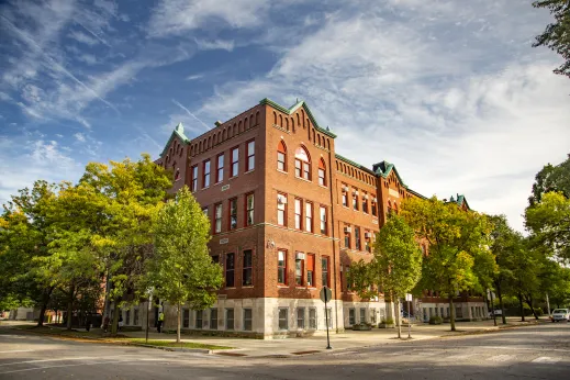 brick apartment building on corner of residential streets with trees surrounding it in Brighton Park Chicago