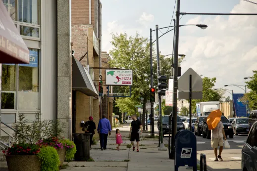 Pedestrians walking on sidewalk in front of local businesses on N Lincoln Ave in Peterson Woods