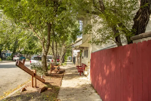 red fence and seesaw along sidewalk on residential side street in Chicago Lawn