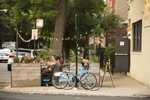 Bicycles parked outside The Winchester with diners on outdoor patio in East Village Chicago