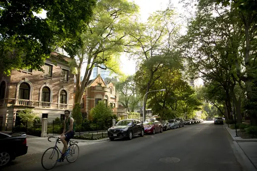 Cars parked in shade by apartments on side street in Lakeview Chicago