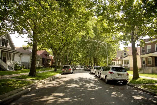 Cars parked on either side of a shady one way street in North Park Chicago