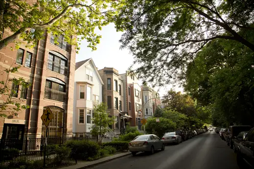 Cars parked in front of apartments on the shady side of the street in Lakeview Chicago