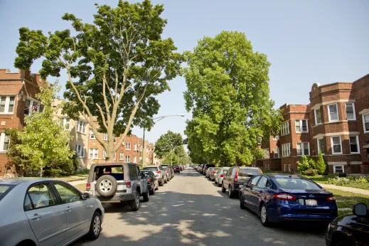 Cars parked on one way street with apartment buildings on either side in Portage Park