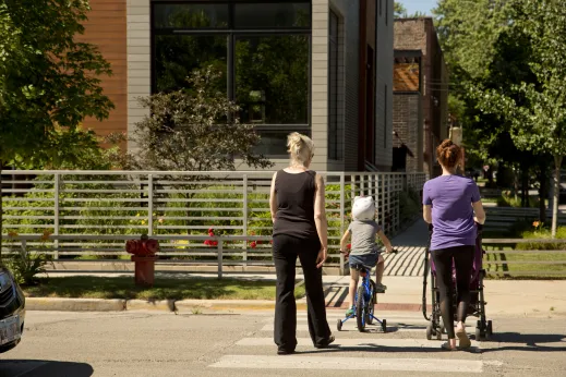 Child riding a bike with training wheels and women walking behind crosswalk in Ukrainian Village Chicago