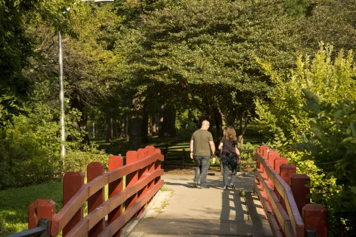 Couple crossing pedestrian footbridge in park in North Mayfair