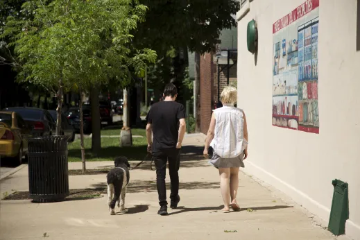 Couple walking dog next to Fiores Delicatessen exterior in Ukrainian Village Chicago