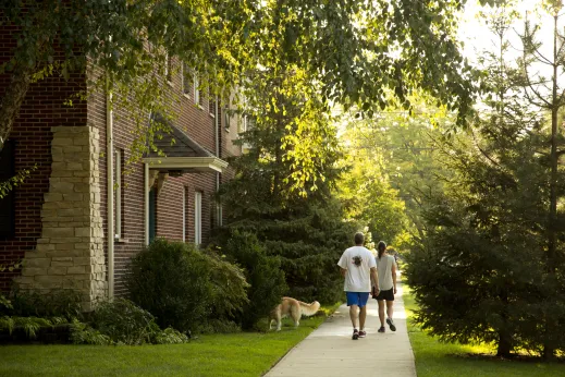 Couple walking golden retriever on sidewalk in Sauganash