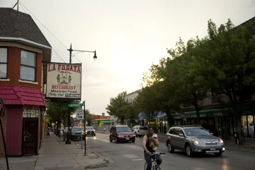 Cyclist and cars on busy neighborhood street in Albany Park Chicago