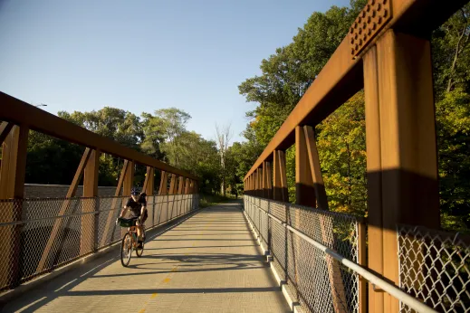 Cyclist crossing the bridge in forest preserve in Edgebrook Chicago