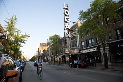 Cyclist rides across from Logan Theatre in Logan Square Chicago