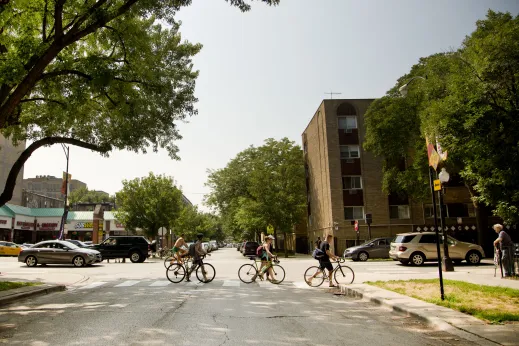 Cyclists walking bikes across intersection with apartments in the background in Margate Park