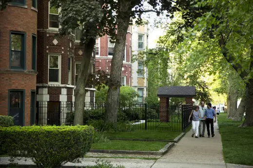 Family walking on sidewalk by apartment buildings in Rogers Park Chicago