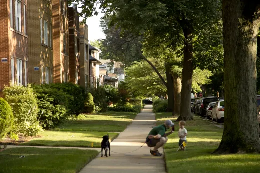 Father and son walking dog on sidewalk in front of apartments in Arcadia Terrace