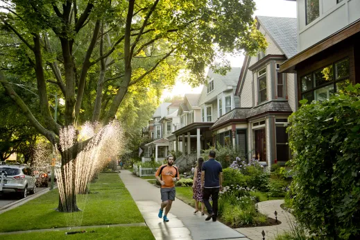 Jogger and sprinkler in front lawns of apartments in Lincoln Square Chicago