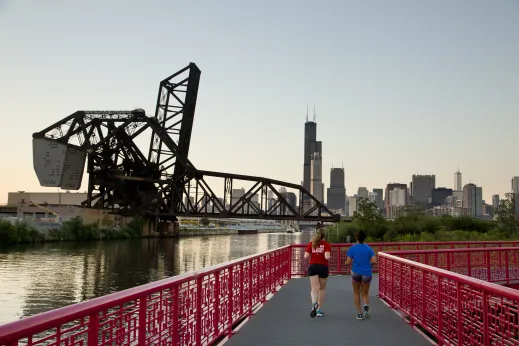 Joggers running on Ping Tom Park boardwalk on South Branch of Chicago River in Chinatown