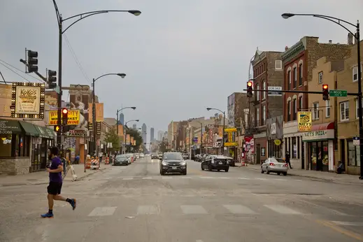 Man jogging on N Wood St crosswalk at W Chicago Ave traffic light in East Village