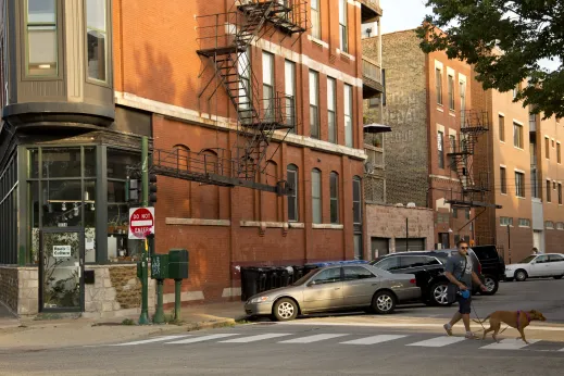 Man walking his dog across intersection in Noble Square Chicago