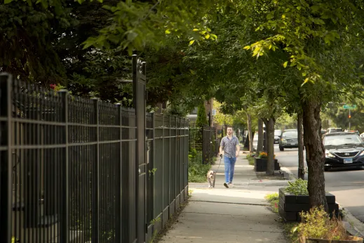 Man walking dog near wrought iron fences and apartments buildings in Lakewood Balmoral