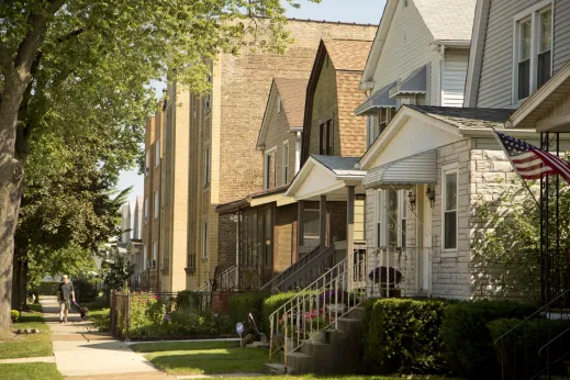 Man walking dog on sidewalk in front of apartments and homes in Jefferson Park Chicago