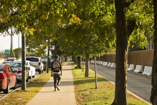 Man walking down sidewalk by Dan Ryan Expressway I-90 and apartments in Fuller Park Chicago