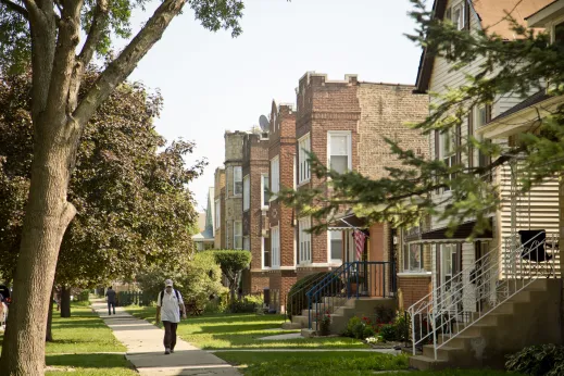 Man walking down sidewalk in front of apartments and single family homes in Mayfair Chicago